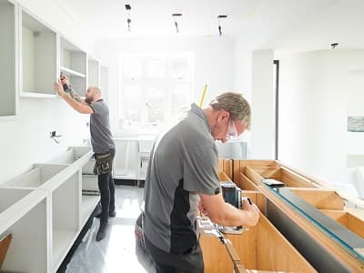 Installers fitting cabinetry and countertops